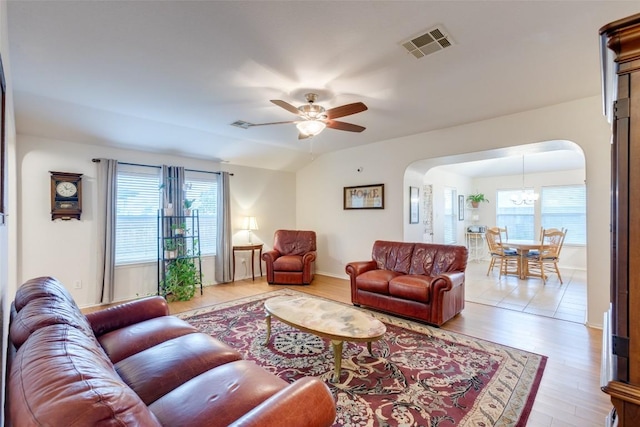 1312 Kothman Dr, Hutto, TX 78634 - living room with arched walkways, a ceiling fan, light wood-type flooring, and a chandelier