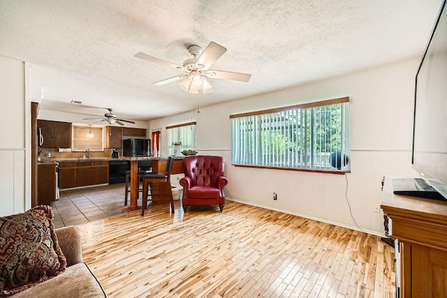 914 Hermitage Dr, Austin, TX 78753 - living area featuring light wood-style floors, a textured ceiling, and a ceiling fan