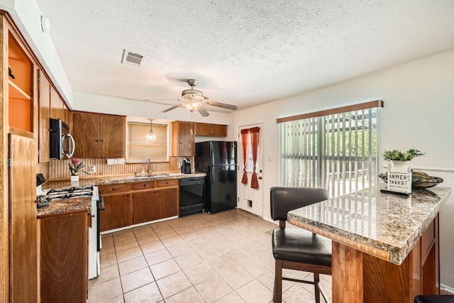 914 Hermitage Dr, Austin, TX 78753 - kitchen with black appliances, brown cabinetry, a ceiling fan, a textured ceiling, and light tile patterned floors