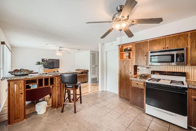 914 Hermitage Dr, Austin, TX 78753 - kitchen with stainless steel microwave, gas range gas stove, open shelves, ceiling fan, and an office area