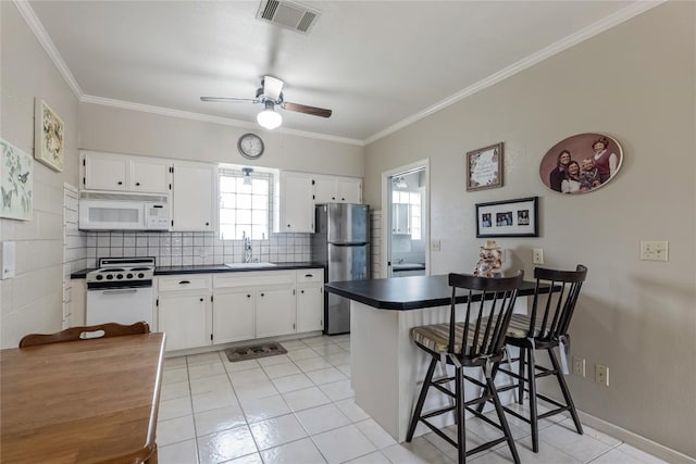 500 N Main St N, Burnet, TX 78611 - kitchen featuring white appliances, dark countertops, a peninsula, a ceiling fan, and ornamental molding