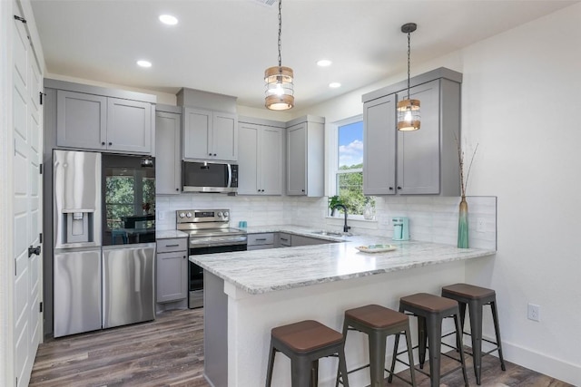 1156 Timberlane Dr, Canyon Lake, TX 78133 - kitchen featuring appliances with stainless steel finishes, gray cabinetry, a peninsula, decorative backsplash, and a kitchen bar