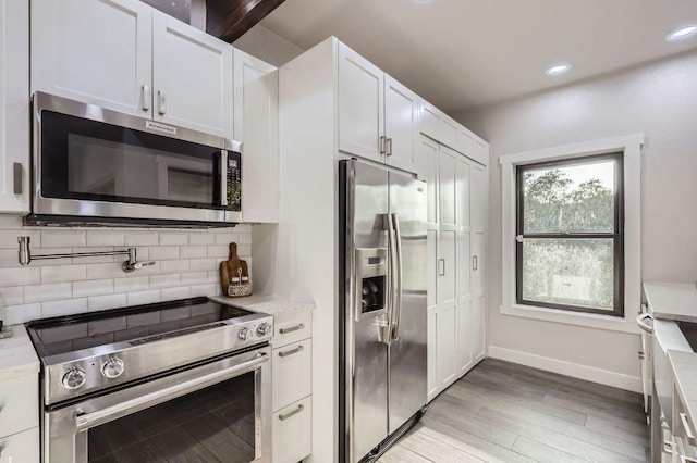 8200 Neely Dr Unit 160, Austin, TX 78759 - kitchen featuring appliances with stainless steel finishes, white cabinets, light wood-style flooring, tasteful backsplash, and light stone countertops