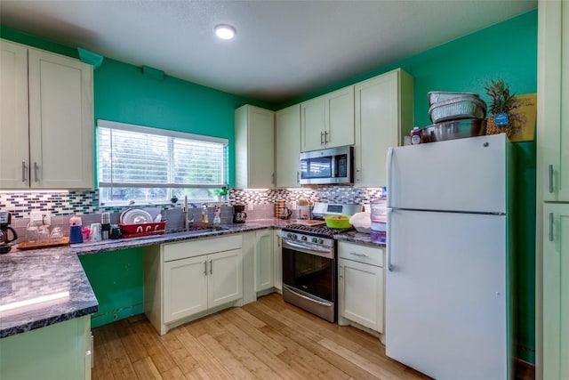 130 Los Arcos Rd, Elgin, TX 78621 - kitchen featuring stainless steel appliances, light wood finished floors, decorative backsplash, and white cabinetry