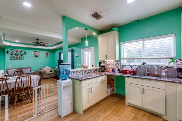 130 Los Arcos Rd, Elgin, TX 78621 - kitchen with backsplash, light wood-style flooring, ceiling fan, dark stone countertops, and open floor plan