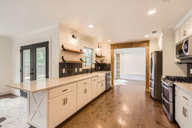 1511 Wilson Heights Dr, Austin, TX 78746 - kitchen with appliances with stainless steel finishes, a peninsula, light countertops, white cabinets, and crown molding