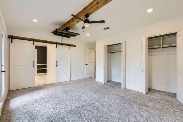 1511 Wilson Heights Dr, Austin, TX 78746 - unfurnished bedroom featuring a barn door, carpet flooring, two closets, beam ceiling, and recessed lighting