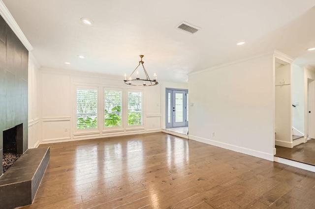1511 Wilson Heights Dr, Austin, TX 78746 - unfurnished living room featuring crown molding, a chandelier, hardwood / wood-style floors, a fireplace, and recessed lighting