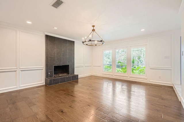 1511 Wilson Heights Dr, Austin, TX 78746 - unfurnished living room featuring a decorative wall, hardwood / wood-style flooring, a chandelier, crown molding, and a tiled fireplace