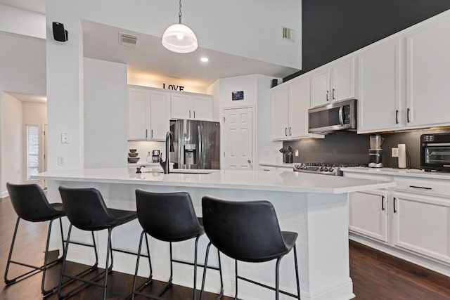 9024 Wildwater Way, Round Rock, TX 78681 - kitchen featuring appliances with stainless steel finishes, light countertops, a breakfast bar area, white cabinetry, and dark wood-type flooring