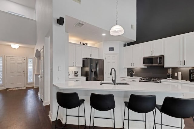 9024 Wildwater Way, Round Rock, TX 78681 - kitchen with appliances with stainless steel finishes, a high ceiling, a breakfast bar area, light countertops, and white cabinets