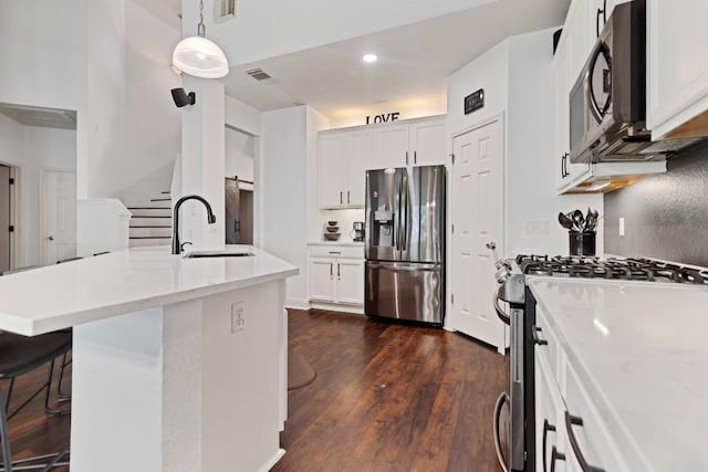 9024 Wildwater Way, Round Rock, TX 78681 - kitchen featuring appliances with stainless steel finishes, dark wood-type flooring, white cabinetry, a breakfast bar area, and recessed lighting