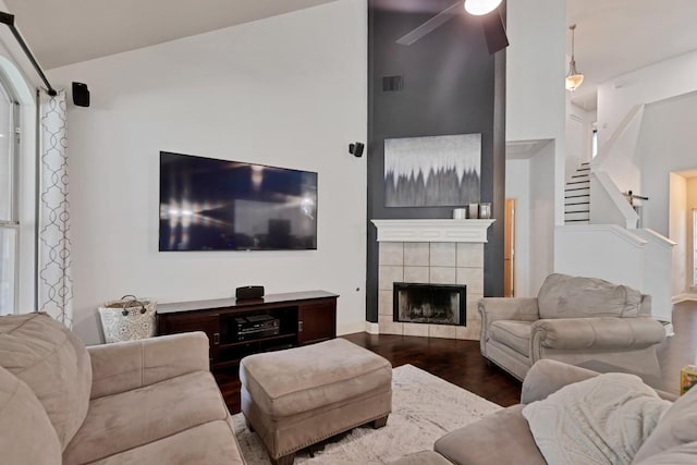 9024 Wildwater Way, Round Rock, TX 78681 - living room with dark wood-type flooring, a ceiling fan, a tiled fireplace, and stairs