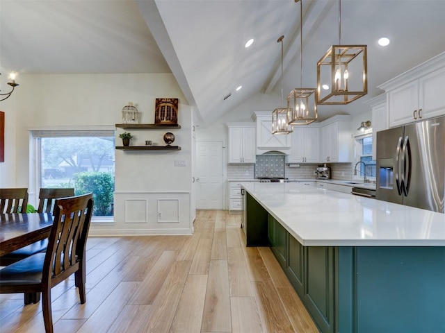 910 Blue Spring Cir, Round Rock, TX 78681 - kitchen with stainless steel fridge, a chandelier, white cabinets, light countertops, and wainscoting