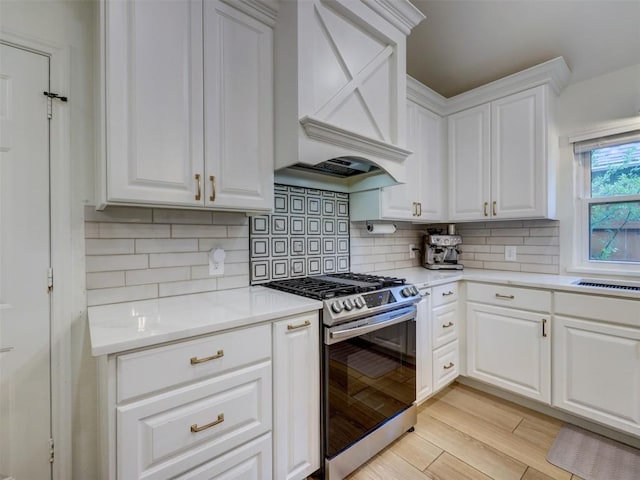910 Blue Spring Cir, Round Rock, TX 78681 - kitchen with gas range, custom exhaust hood, white cabinetry, decorative backsplash, and light wood-style flooring