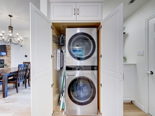 910 Blue Spring Cir, Round Rock, TX 78681 - laundry area with stacked washing machine and dryer, a chandelier, and light wood-style flooring