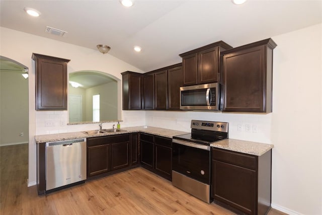 232 Reagor Dr, Taylor, TX 76574 - kitchen with appliances with stainless steel finishes, arched walkways, lofted ceiling, backsplash, and dark brown cabinetry