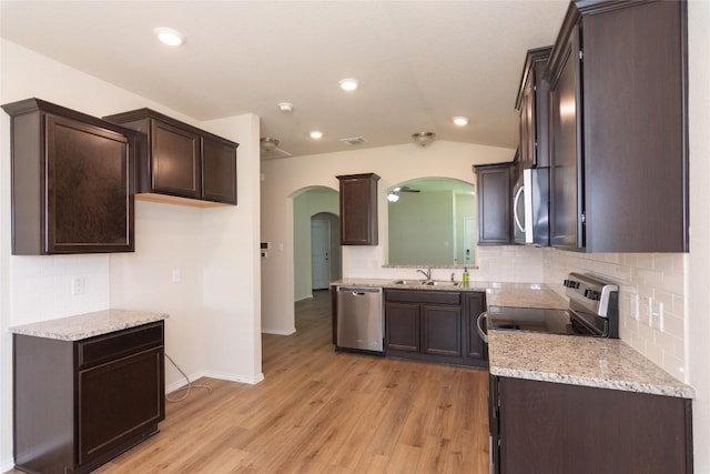 232 Reagor Dr, Taylor, TX 76574 - kitchen with stainless steel appliances, arched walkways, dark brown cabinetry, tasteful backsplash, and light wood finished floors