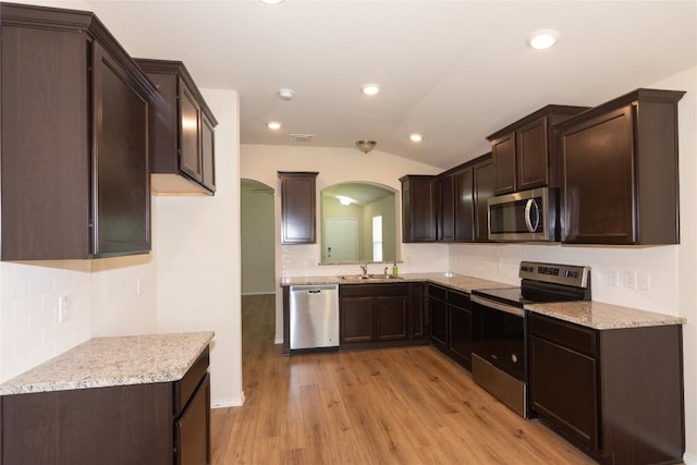 232 Reagor Dr, Taylor, TX 76574 - kitchen with appliances with stainless steel finishes, arched walkways, lofted ceiling, backsplash, and dark brown cabinets