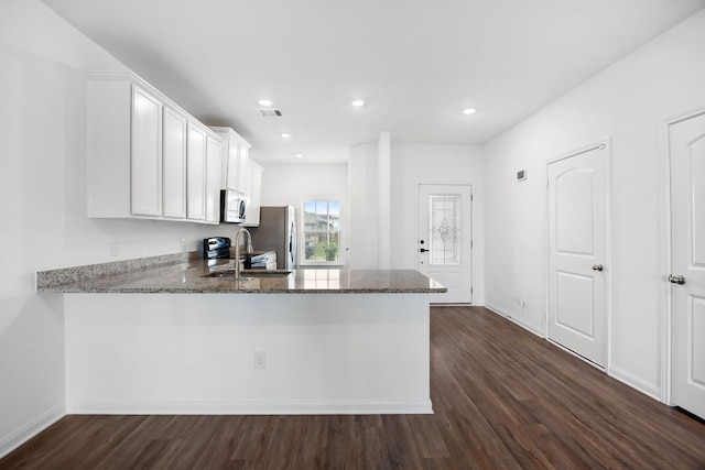 19512 Andrew Jackson St, Manor, TX 78653 - kitchen with stainless steel appliances, stone countertops, dark wood-style flooring, white cabinetry, and recessed lighting