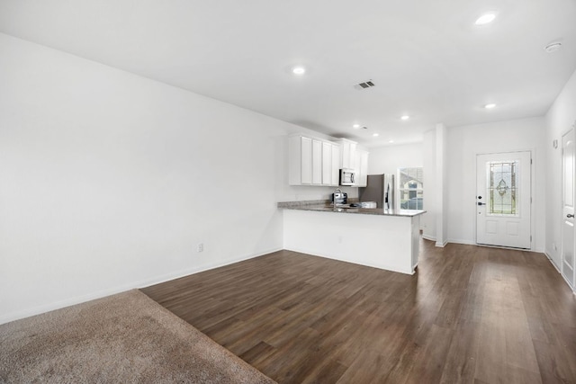 19512 Andrew Jackson St, Manor, TX 78653 - kitchen featuring dark wood finished floors, white cabinets, stainless steel appliances, a peninsula, and recessed lighting