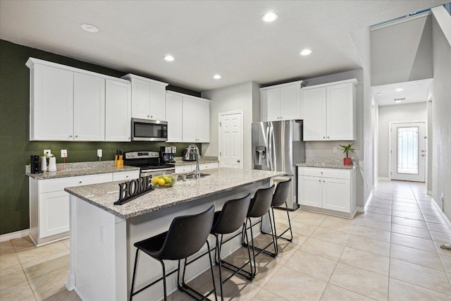 604 John Muir Trl, Leander, TX 78641 - kitchen with appliances with stainless steel finishes, light tile patterned flooring, recessed lighting, a kitchen bar, and white cabinetry