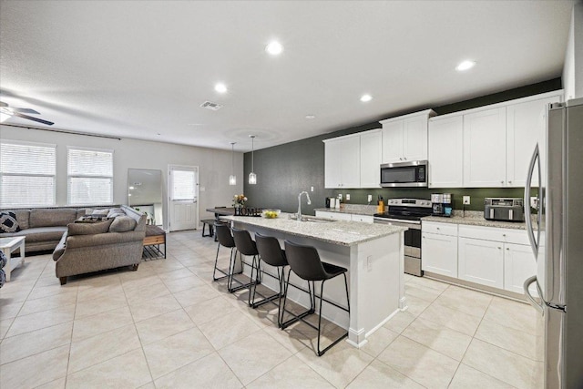 604 John Muir Trl, Leander, TX 78641 - kitchen with stainless steel appliances, open floor plan, white cabinetry, light stone countertops, and recessed lighting