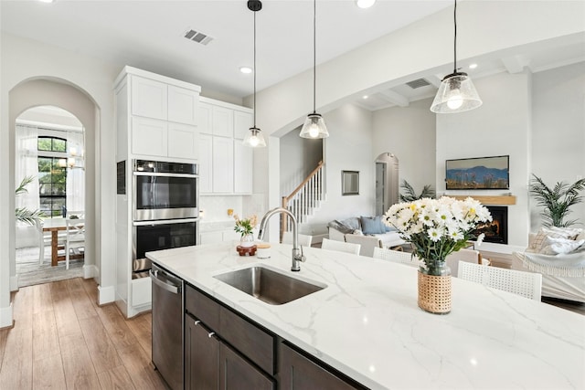 15408 Joseph Dr, Austin, TX 78734 - kitchen with stainless steel appliances, arched walkways, open floor plan, light wood-style flooring, and beam ceiling