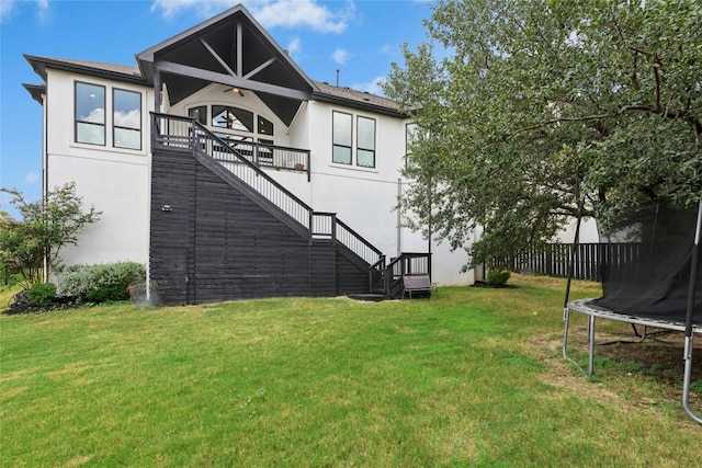 15408 Joseph Dr, Austin, TX 78734 - rear view of house with stairway, a trampoline, a lawn, and stucco siding