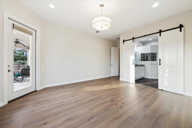 3207 Crystal Falls Pkwy, Leander, TX 78641 - unfurnished bedroom with a barn door, access to exterior, wood finished floors, recessed lighting, and ensuite bathroom