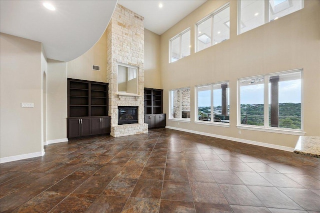 3207 Crystal Falls Pkwy, Leander, TX 78641 - unfurnished living room with plenty of natural light, a high ceiling, a large fireplace, and built in shelves