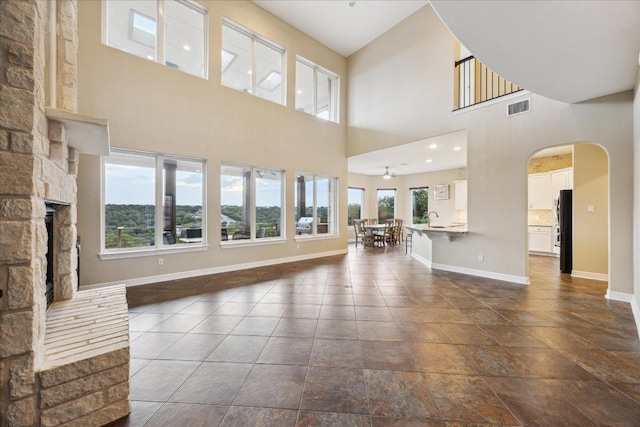 3207 Crystal Falls Pkwy, Leander, TX 78641 - unfurnished living room featuring arched walkways, a fireplace, a towering ceiling, and ceiling fan