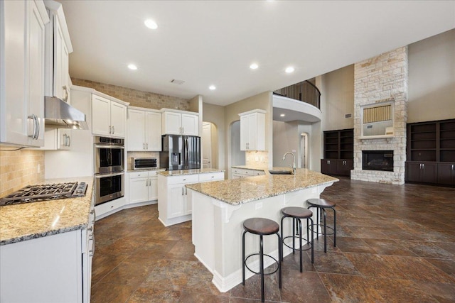 3207 Crystal Falls Pkwy, Leander, TX 78641 - kitchen with stainless steel appliances, stone tile floors, range hood, white cabinets, and recessed lighting