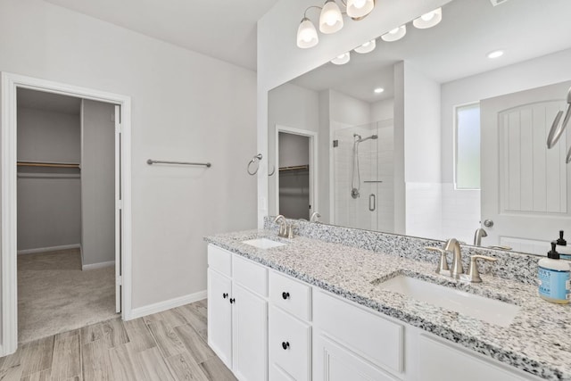 127 Tom Kite Dr, Burnet, TX 78611 - bathroom with a walk in closet, a shower stall, double vanity, and wood finished floors