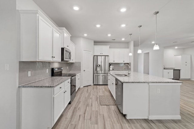 127 Tom Kite Dr, Burnet, TX 78611 - kitchen with stainless steel appliances, light wood-style floors, white cabinets, tasteful backsplash, and recessed lighting