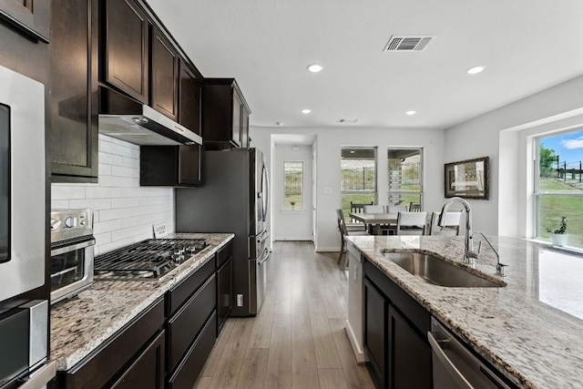 8100 Copper Prairie Bnd, Lago Vista, TX 78645 - kitchen featuring under cabinet range hood, stainless steel appliances, recessed lighting, light wood finished floors, and light stone counters