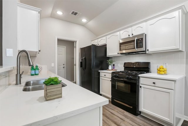 216 Watergate Way, Hutto, TX 78634 - kitchen with black appliances, vaulted ceiling, white cabinets, decorative backsplash, and light countertops