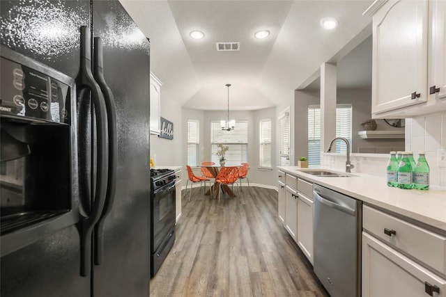 216 Watergate Way, Hutto, TX 78634 - kitchen featuring black appliances, wood finished floors, light countertops, a chandelier, and white cabinetry