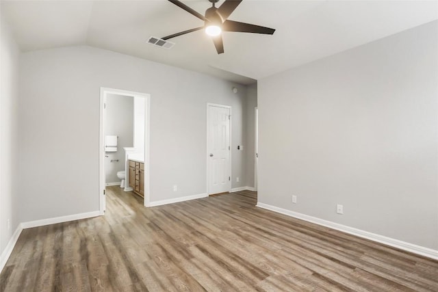 216 Watergate Way, Hutto, TX 78634 - unfurnished bedroom with wood finished floors, vaulted ceiling, ensuite bathroom, and ceiling fan