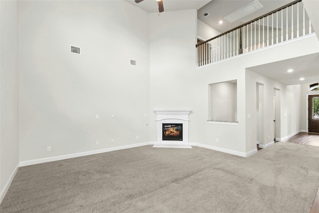 2309 Lone Spur Cv, Round Rock, TX 78665 - unfurnished living room featuring carpet, ceiling fan, a glass covered fireplace, and a towering ceiling
