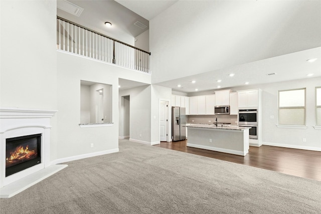 2309 Lone Spur Cv, Round Rock, TX 78665 - unfurnished living room featuring dark colored carpet, a glass covered fireplace, a towering ceiling, recessed lighting, and dark wood-style floors