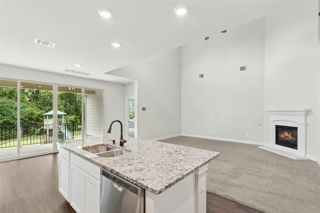 2309 Lone Spur Cv, Round Rock, TX 78665 - kitchen featuring stainless steel dishwasher, a center island with sink, light stone countertops, white cabinetry, and a glass covered fireplace
