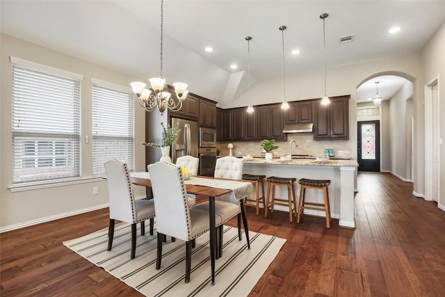 1821 Cherry Glade Trl, Georgetown, TX 78628 - dining room with arched walkways, a chandelier, dark wood-style flooring, vaulted ceiling, and recessed lighting