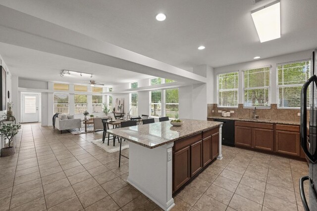 1267 Sanders, Kyle, TX 78640 - kitchen with decorative backsplash, a kitchen breakfast bar, light tile patterned floors, light stone counters, and recessed lighting
