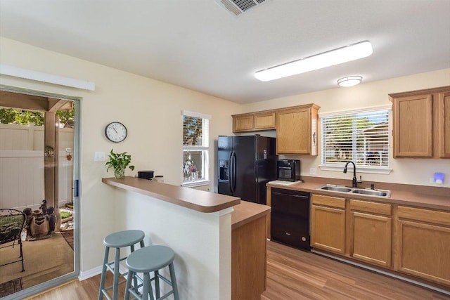 401 Buttercup Creek Blvd Unit 1904, Cedar Park, TX 78613 - kitchen with a breakfast bar, light wood finished floors, black appliances, light countertops, and a peninsula