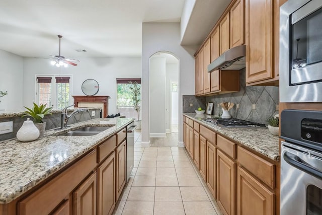 112 Mcbride Ln, Cedar Park, TX 78613 - kitchen with appliances with stainless steel finishes, under cabinet range hood, a ceiling fan, tasteful backsplash, and arched walkways