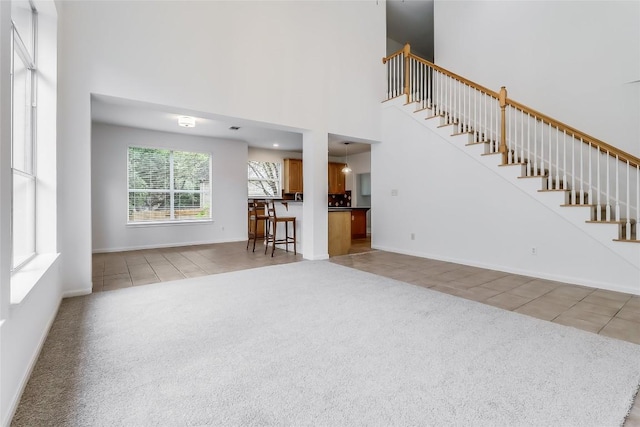12608 Chittim Cir, Austin, TX 78732 - tiled living room featuring carpet, stairs, and a high ceiling