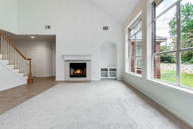 12608 Chittim Cir, Austin, TX 78732 - unfurnished living room with plenty of natural light, high vaulted ceiling, a tile fireplace, stairway, and carpet