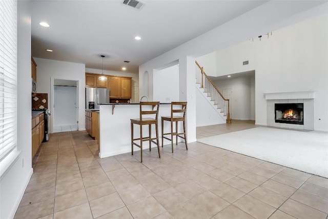 12608 Chittim Cir, Austin, TX 78732 - kitchen featuring a kitchen bar, dark countertops, stainless steel fridge with ice dispenser, recessed lighting, and a fireplace