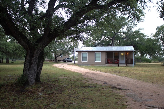 600 Jim Bowie Dr, Spicewood, TX 78669 - view of front of house with covered porch, a front yard, and a metal roof